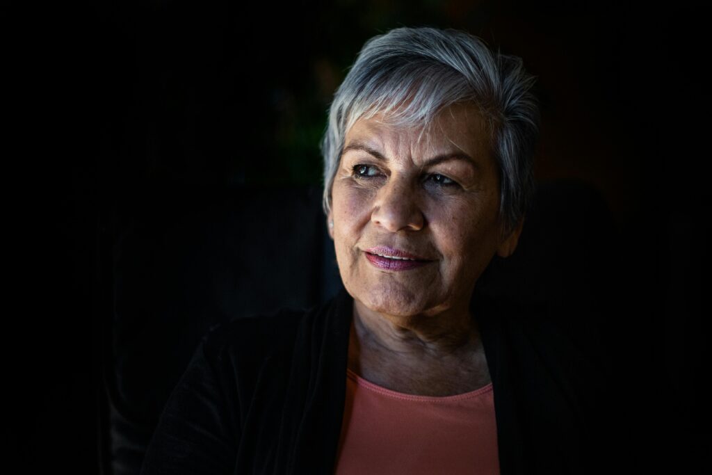 Om Oss Elderly woman with gray hair looking thoughtfully, showcasing wisdom and grace.