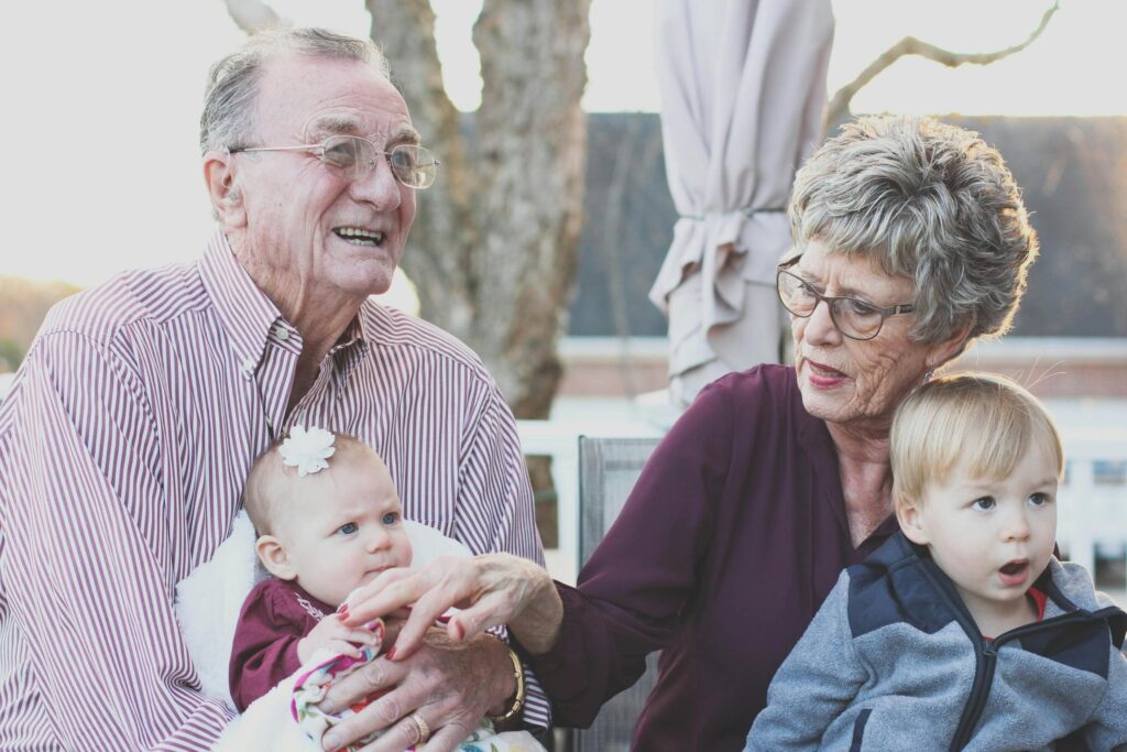 Om Oss Grandparents spending joyful moments with their grandchildren in an outdoor setting, captured candidly.